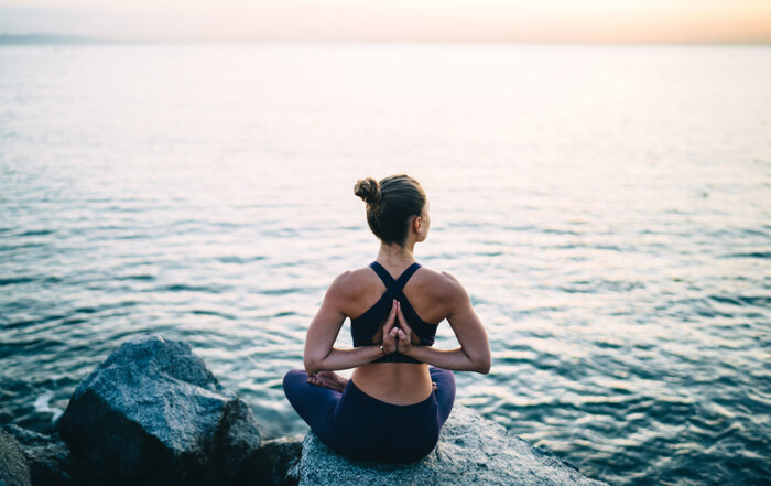 Woman in yoga pose sitting by the sea
