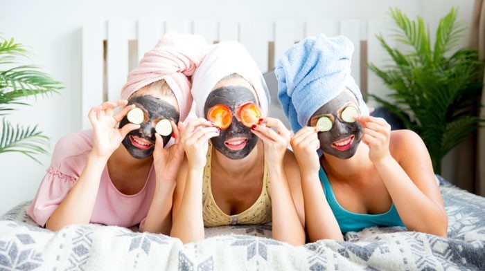 Three friends laying on bed wearing face masks