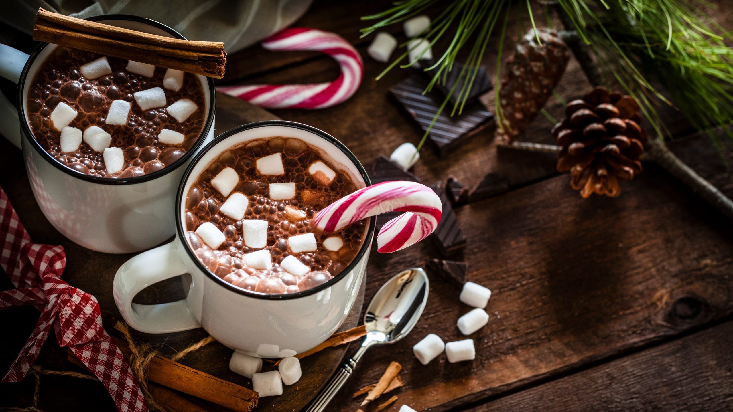 Two mugs of hot chocolate with marshmallows and candy canes