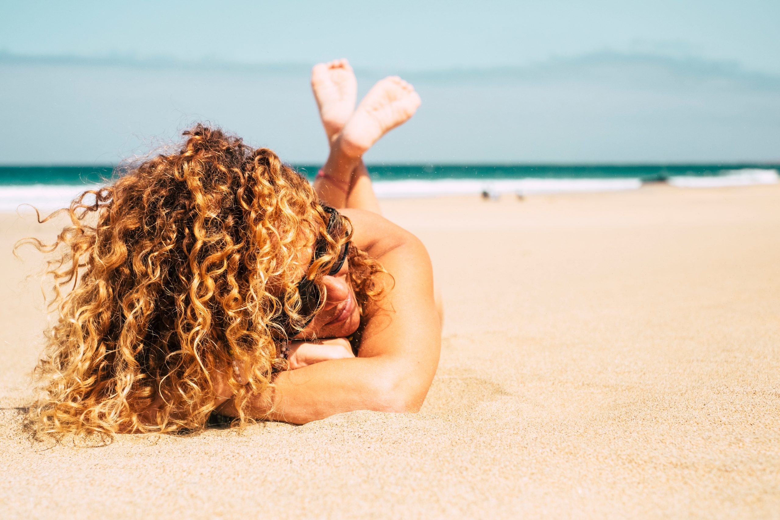 Woman With Curly Hair Relaxing On Beach