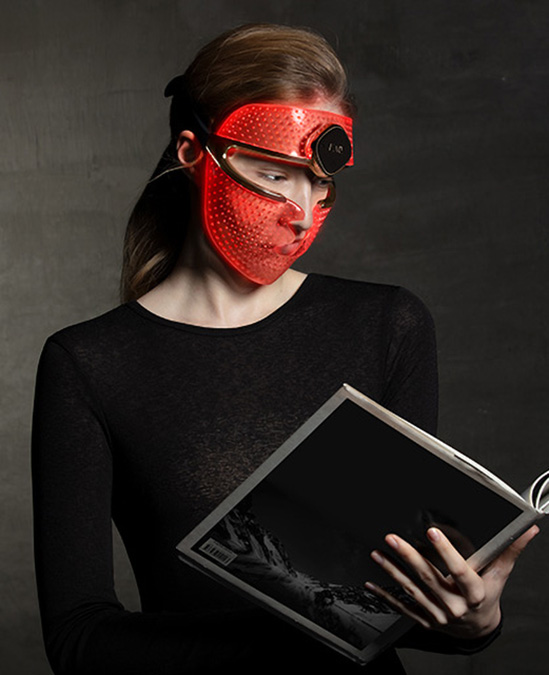 A model using the FAQ 202 LED face mask while reading a magazine