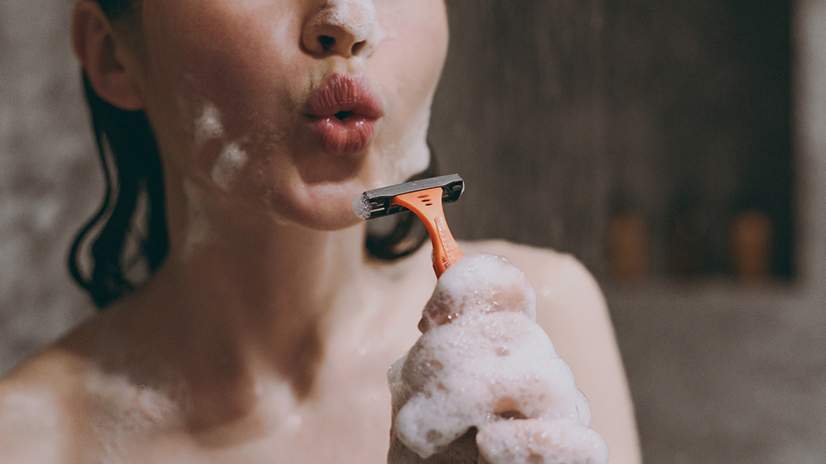 A closeup of a woman shaving