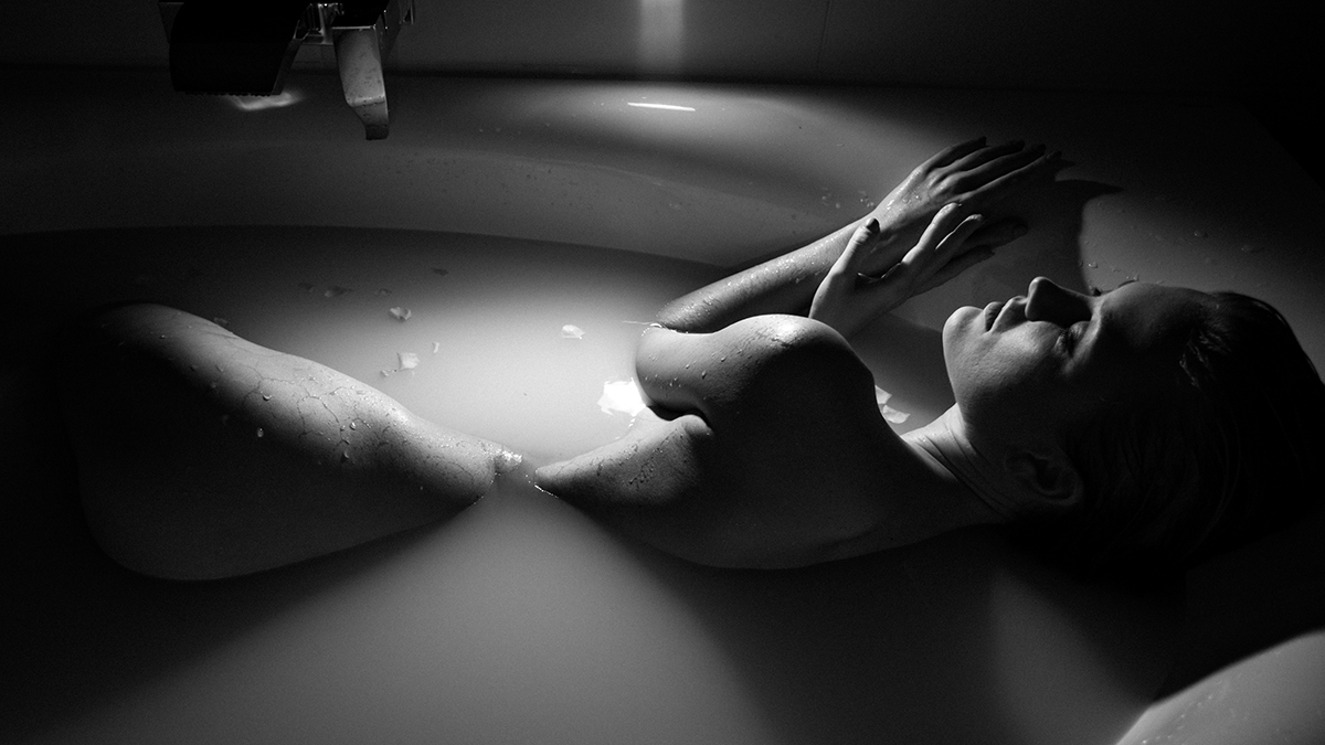 Black and white photo of a sexy woman in milk bath