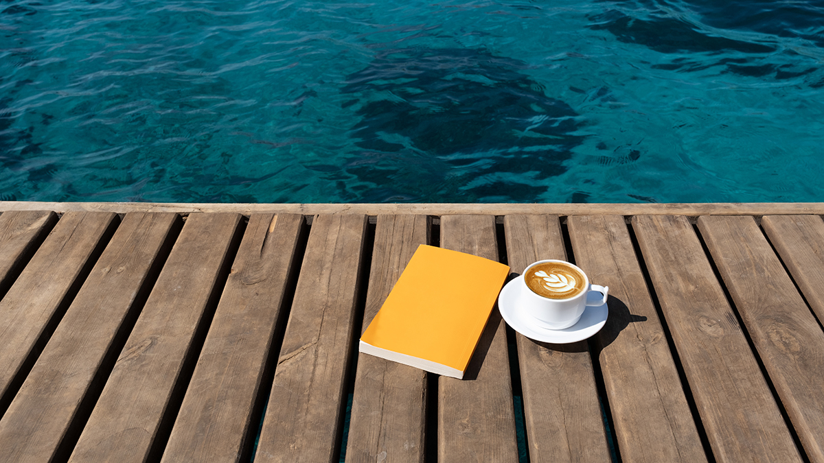 Book and a coffee cup on a dock