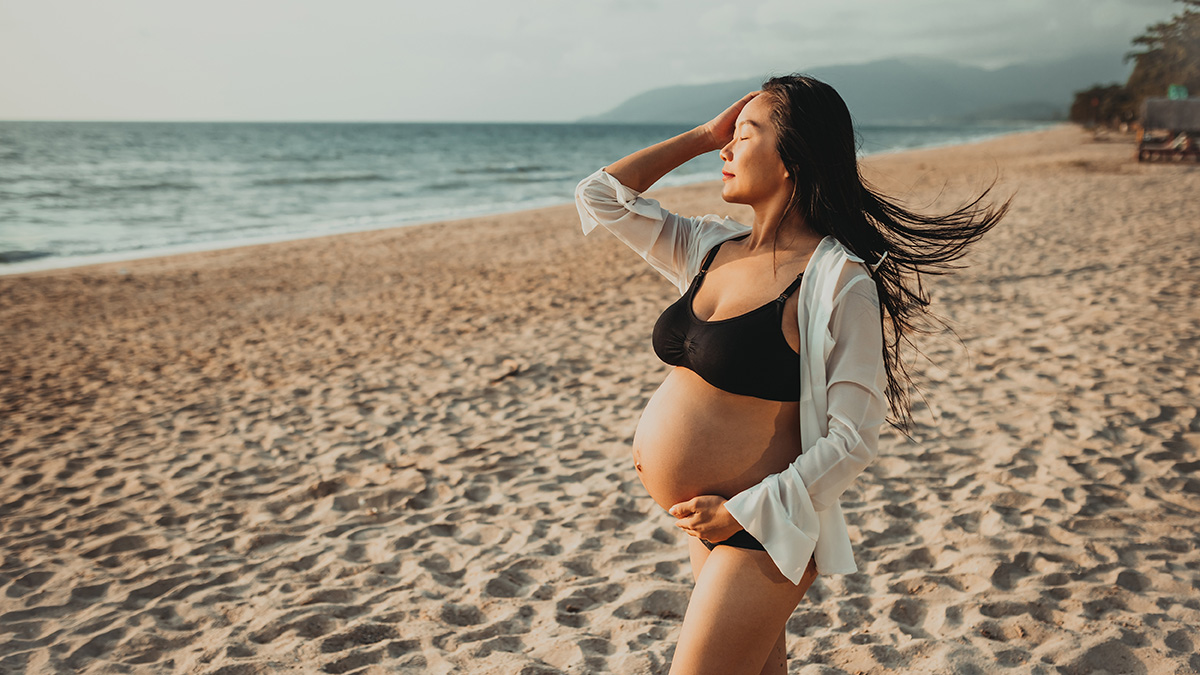 Beautiful pregnant woman in a bikini on a sandy beach