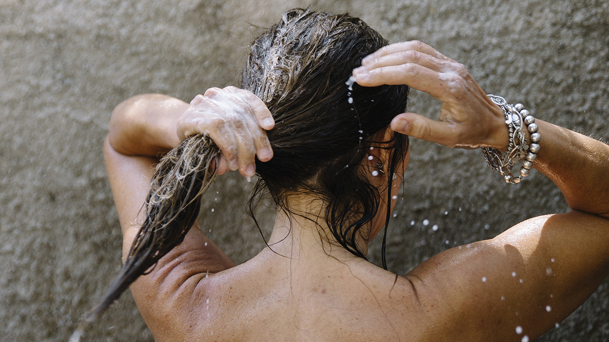 Woman shampooing hair under shower