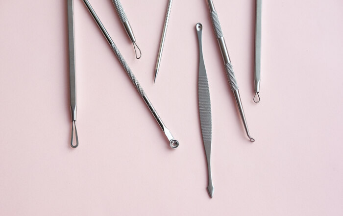 Tools for removing blackheads and acne on pink surface