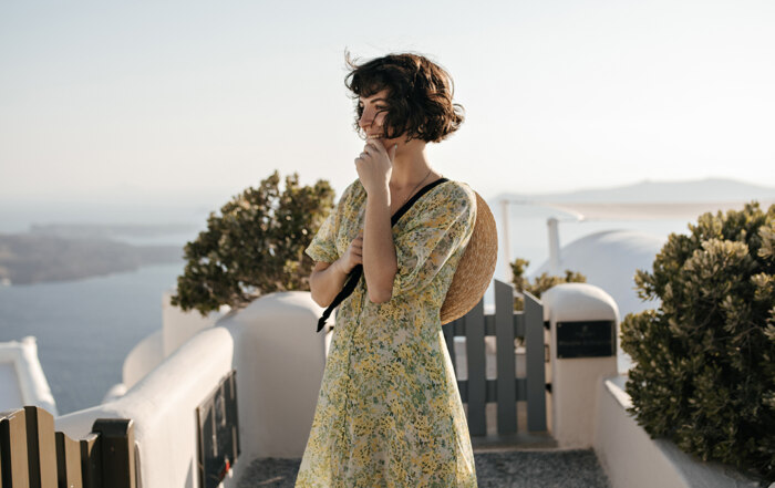 A photo of a young woman in a romantic dress in a village overlooking the sea