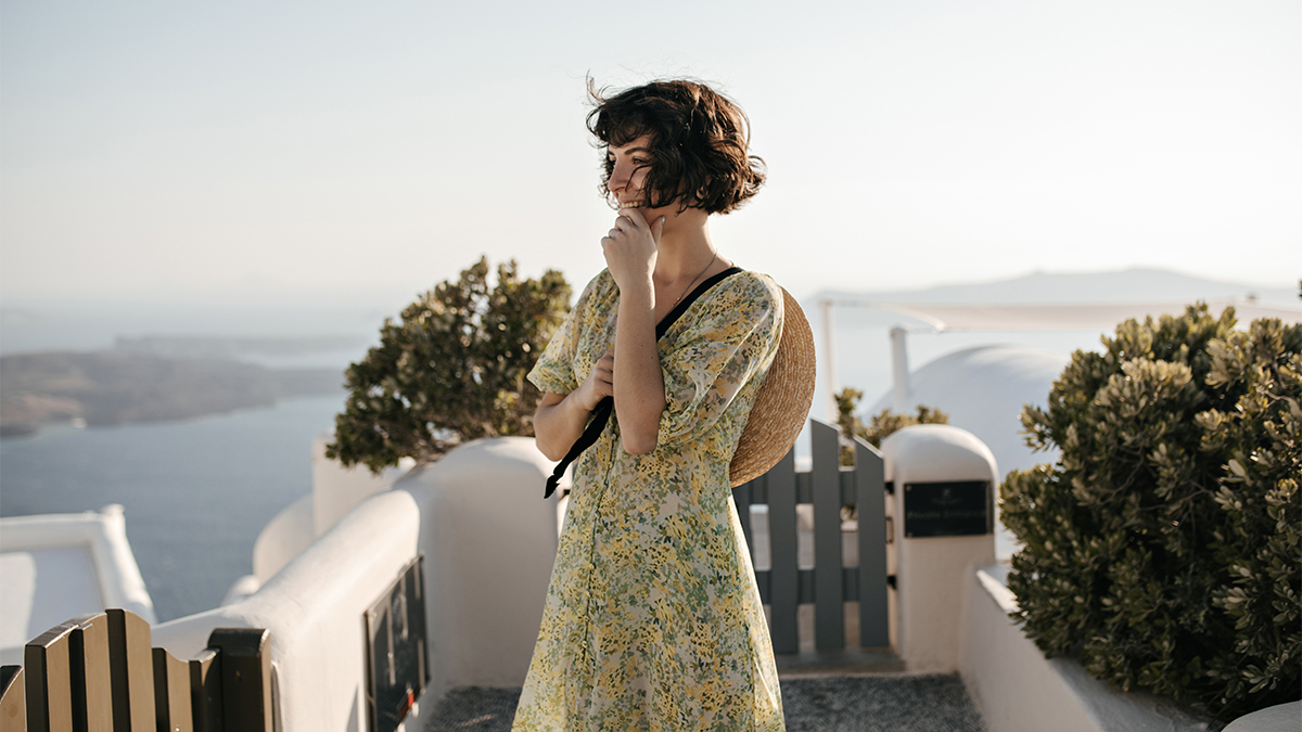 A photo of a young woman in a romantic dress in a village overlooking the sea