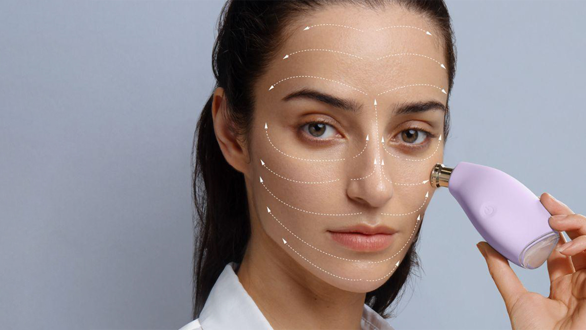 A model using FOREO KIWI derma on her face, with arrows drawn on her face in the direction the product should glide