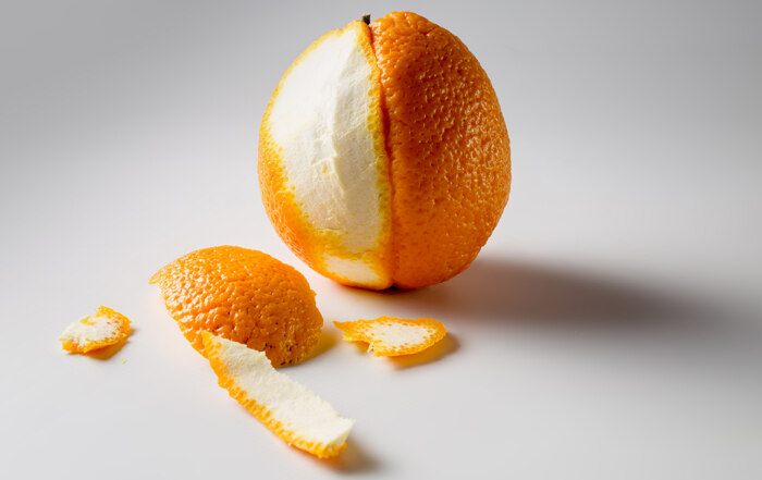 A photo of a half-peeled orange on a white surface