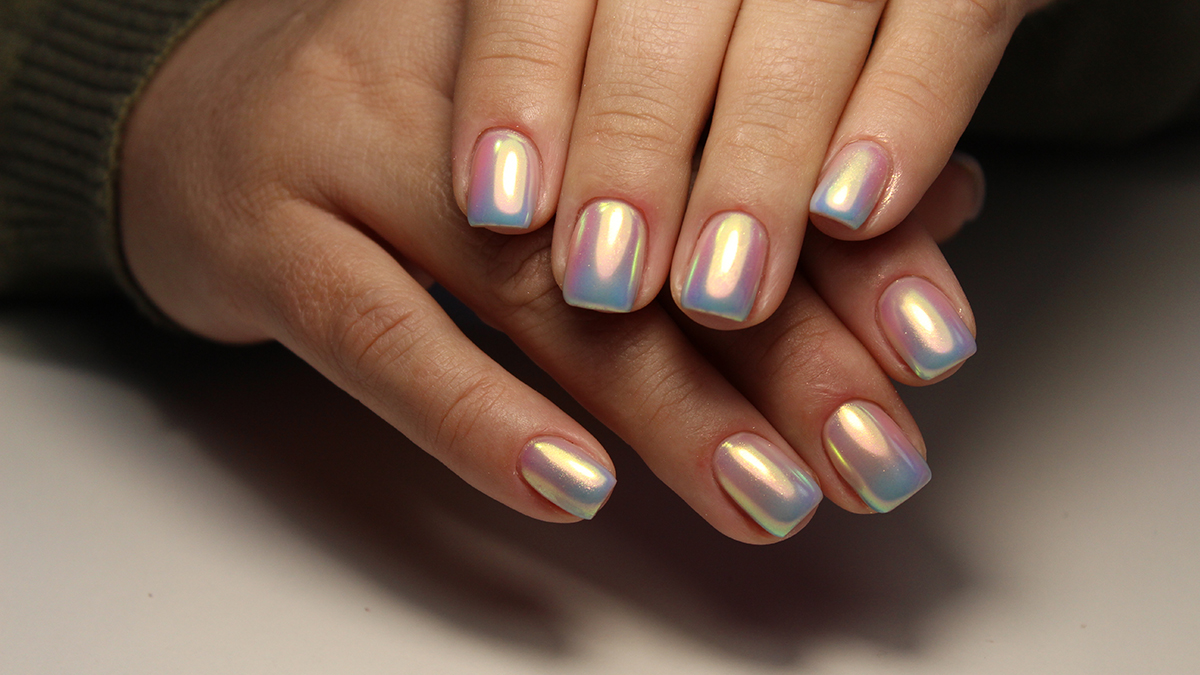 Hands with freshly manicured nails in chrome nail trend